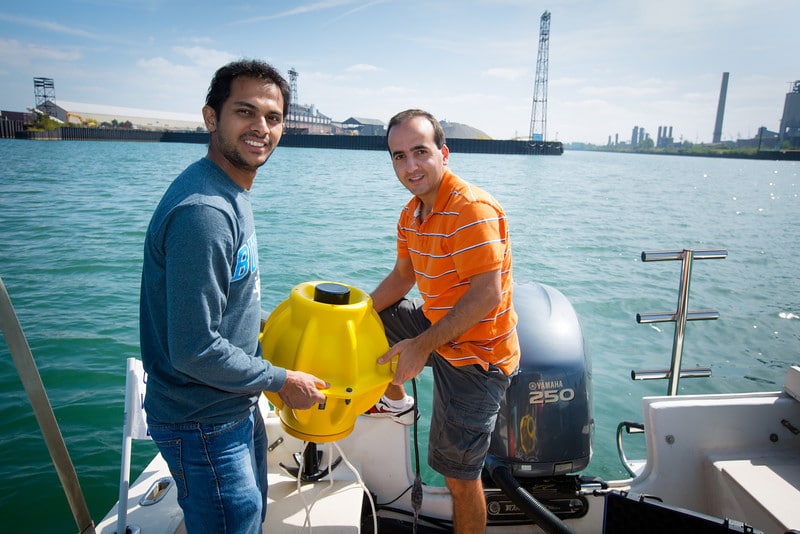 Electrical Engineering Graduate Students Hovannes Kulhandjian and Zahed Hossain in the lab (boat) of Tommaso Melodia’s WINES Lab Research on Lake Erie  (Photo: Douglas Levere / University of Buffalo)