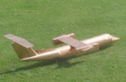 A gold 1/10th scale model of the aircraft sitting on grass