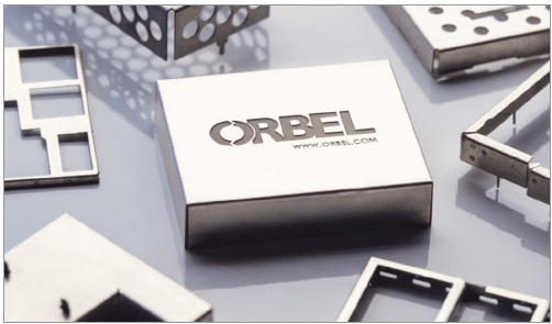 A photograph of a custom board level shield stamped with Orbel's logo. 