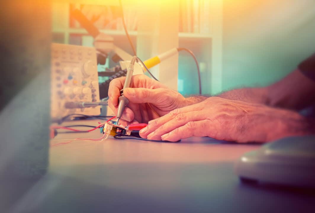 Hands of a senior engineer testing electronic equipment in hardware service center.
